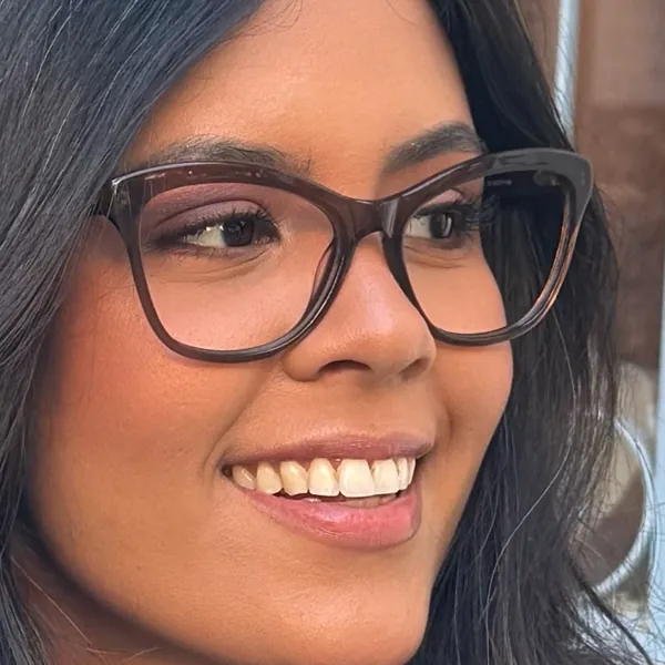 Mulher sorrindo, de óculos de grau com armação marrom